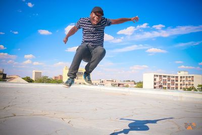 Full length of man jumping in city against sky