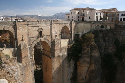 Arch bridge over buildings against sky