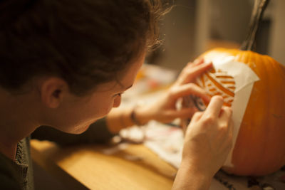 Close-up of woman carving pumpkin during halloween