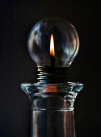 Close-up of burning candle against black background