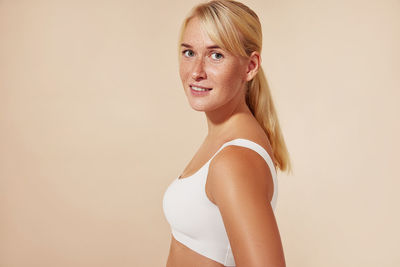 Portrait of young woman standing against wall