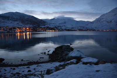 Scenic view of lake by snowcapped mountains against sky during winter