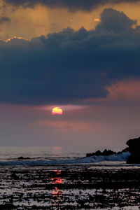 Scenic view of sea against cloudy sky during sunset