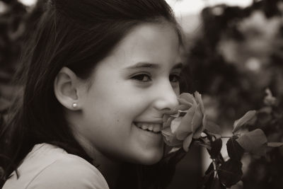 Side view of smiling girl smelling flower