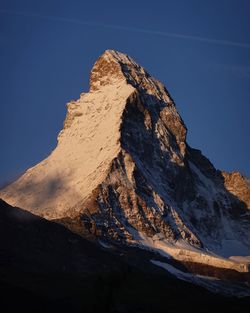 Shadow of rocks on mountain against blue sky