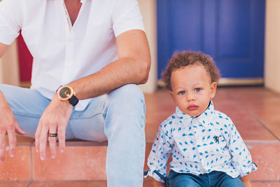 Dad and toddler sitting on the steps with focus on baby boy