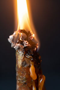 Close-up of burning candle against black background
