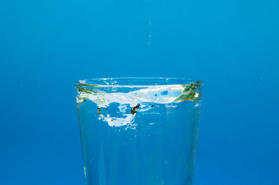 Close-up of drinking glass against blue background