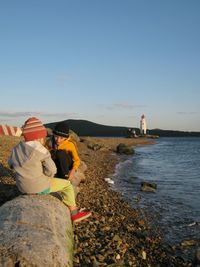 Rear view of people on beach against clear sky