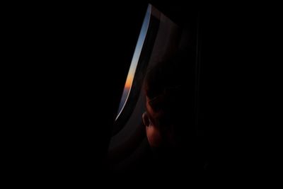 Close-up of girl looking through airplane window