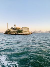 Sea by buildings against clear sky