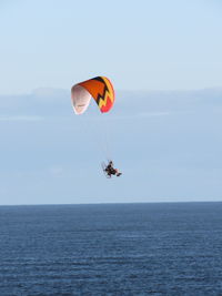 People paragliding over sea against sky