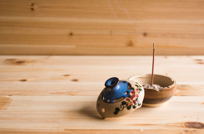 Smoke emitting burning incense in pot on wooden table