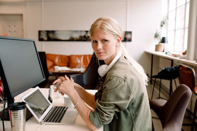 Portrait of female entrepreneur sitting on chair in workplace