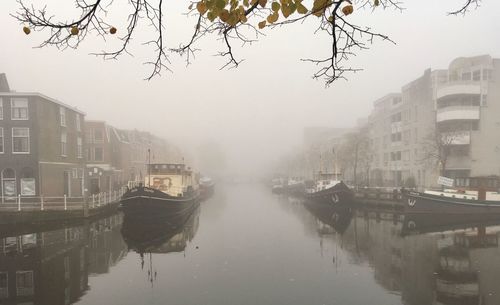 Canal in city against sky