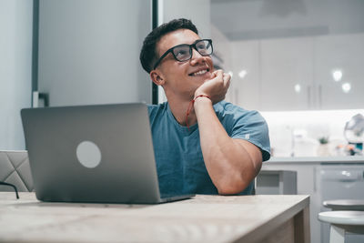 Young man using laptop while sitting on table