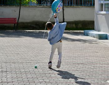 Rear view of boy standing on footpath
