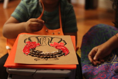 Cropped image of mother and son making craft on table