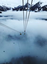 Overhead cable cars hanging over clouds