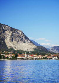 Scenic view of sea by buildings against clear blue sky
