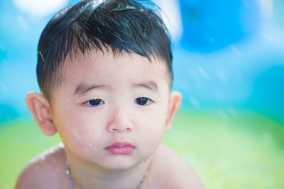 Cute shirtless boy in sprinkler at playground