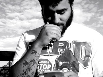 Close-up of bearded man using mobile phone against sky