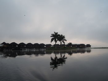 Silhouette palm trees by lake against sky at inle lake