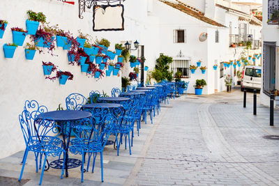 Empty chairs and tables on sidewalk by building in city