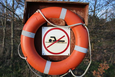 Close-up of no swimming sign amidst life belt