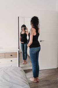 Full length of woman standing on bed at home