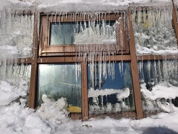 Icicles on window of abandoned house during winter
