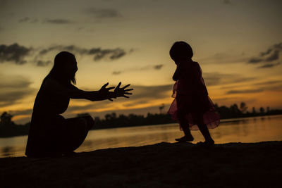 Silhouette people on beach against sky during sunset