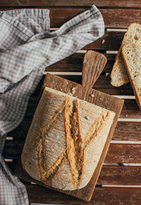 Top view of freshly baked bread loaf on rustic wooden cutting board and napkin