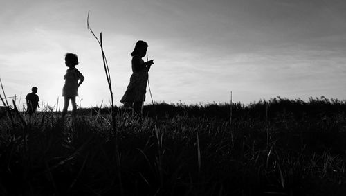 Silhouettes of village children playing on the edge of the pond in the afternoon