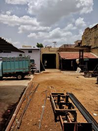 Empty road by buildings against sky