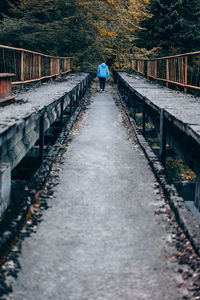 Rear view of man walking on footbridge