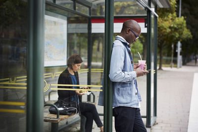 Mid adult commuters waiting at bus stop in city