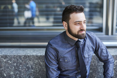 Thoughtful businessman looking away while sitting on seat in office