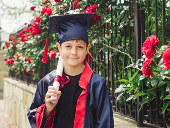 Portrait of woman wearing graduation gown standing in park