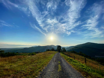 Road amidst field against sky