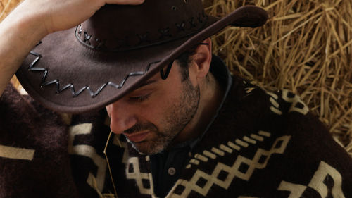 Tired cowboy leaning on hay bale