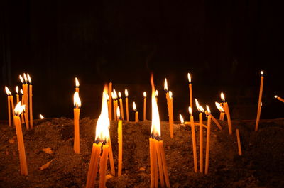 Close-up of burning candles against black background