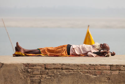 Man relaxing on shore against sky