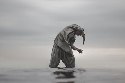 Man exercising in sea against sky