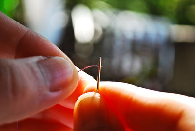 Close-up of cropped hands threading sewing needle