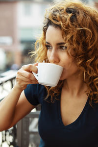 Young moroccan woman, with curly brown hair, sitting in an outdoor café in mainz, drinking coffee