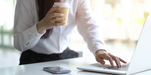 Midsection of man using laptop on table