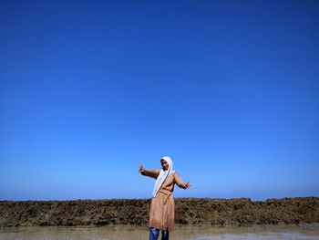 Rear view of woman standing against clear blue sky