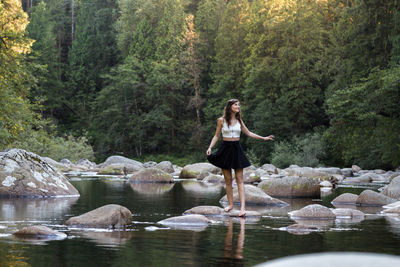 Woman standing on rock by lake in forest