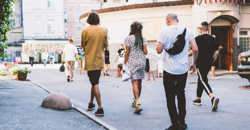 Rear view of people walking on road in city